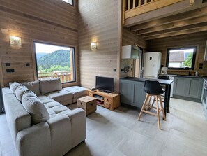 Un intérieur moderne comprenant un canapé, un téléviseur, des meubles en bois et un coin repas.
