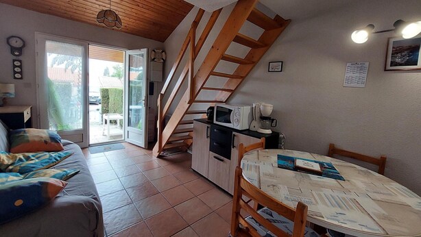 Ein kompakter Wohnraum mit Sofa, Esstisch, Küchenzeile und Treppe.