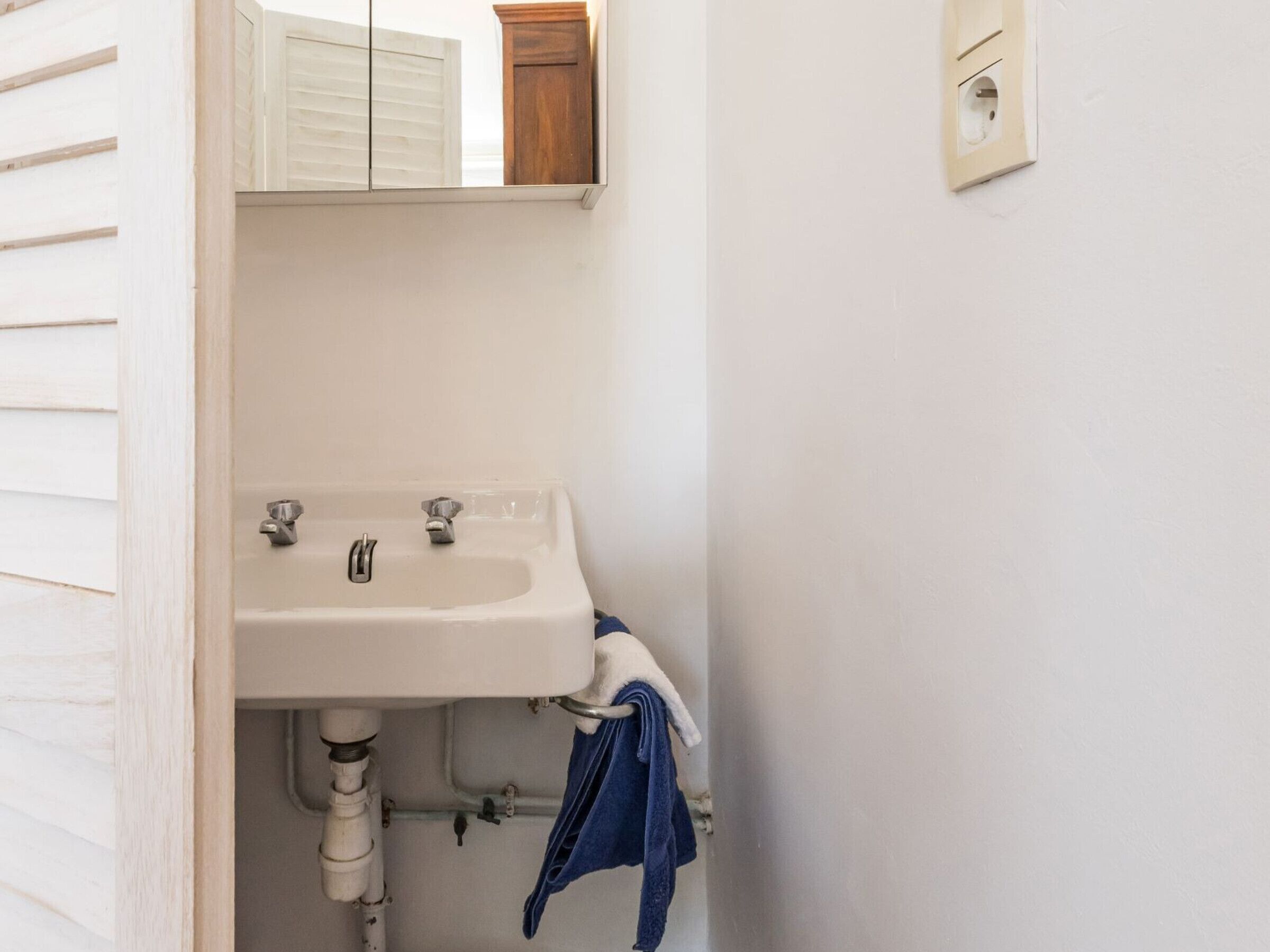 A bathroom with a white sink, a mirror above it, and a wooden cabinet.