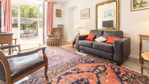 A living room with a sofa, armchairs, a coffee table, a TV, and a large mirror. - Cozy cottage near the beach - 5 guests (Pornic)