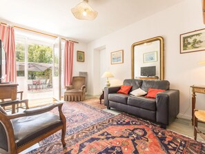 A living room with a sofa, armchairs, a coffee table, a TV, and a large mirror. - Cozy cottage near the beach - 5 guests (Pornic)