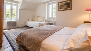 A bedroom with a bed, a window, a radiator, a lamp, and a painting on the wall. - Cozy cottage near the beach - 5 guests (Pornic)