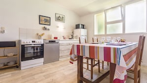 A kitchen with a stove, oven, dishwasher, and a dining table set for four. - Cozy cottage near the beach - 5 guests (Pornic)