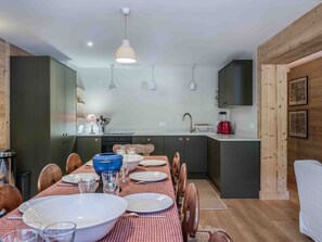 A modern kitchen with dark cabinets, a dining table set for six, and a red and white checkered tablecloth. - Apartment in the center - 10 guests (Méribel)