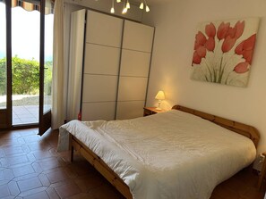 Ein Schlafzimmer mit einem Bett, einem Nachttisch, einer Lampe, einer Schiebetür und einem Blumenbild.