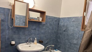 Een badkamer met een wastafel, spiegel en bad.