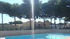 A swimming pool with metal ladders, surrounded by trees and buildings. - Studio cabin near naturist village - 4 guests (Cap d'Agde)