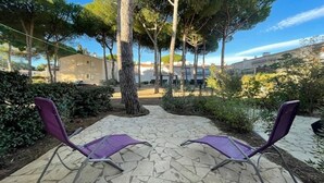 A courtyard with two purple chairs, stone flooring, and trees. - Studio cabin near naturist village - 4 guests (Cap d'Agde)
