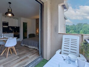 A balcony with a table, chairs, and a view of greenery. - Studio with balcony, parking, pets welcome - 2 guests (Barbotan-les-Thermes)