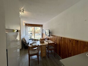 Ein kompakter Wohnbereich mit Essbereich, einem an der Wand montierten Fernseher und Blick durch ein Fenster.