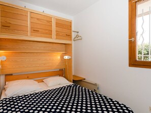 Ein Schlafzimmer mit einem Bett, einem hölzernen Kopfteil, einem Fenster und einer Heizung.