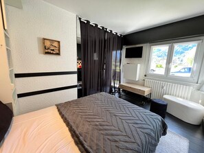 Ein Schlafzimmer mit Bett, Schreibtisch, Stuhl, Fernseher und Fenster mit Blick.