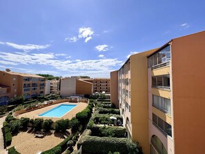 Ein Hotel mit Schwimmbad, umgeben von gepflegten Gärten, mehreren Balkonen und einem wolkenlosen, blauen Himmel.