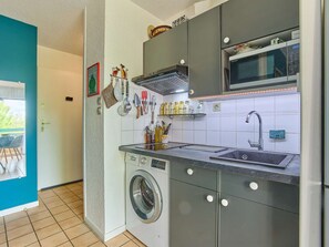 Eine kleine Küche mit Waschmaschine, Mikrowelle und Spüle.