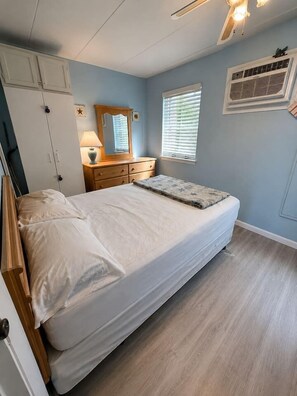 A bedroom with a bed, dresser, mirror, and window with blinds.