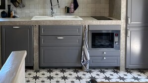 A modern kitchen with grey cabinets, a built-in oven, a microwave, and a tiled backsplash. - Air-conditioned cottage - SPA BBQ (Aix-en-Provence)