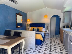 Ein Hotelzimmer mit Bett, Schreibtisch, Spiegel und einer Küchenzeile.