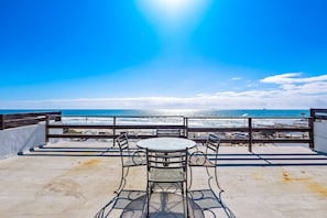 Un balcon avec une table et des chaises donnant sur l’océan.