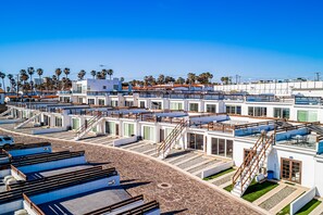 A hotel with multiple levels, outdoor terraces, and a clear view of palm trees. - Bright Dog-friendly Home With Heated Pool, Hot Tub, Streaming, & Ocean Views (Playas de Rosarito)