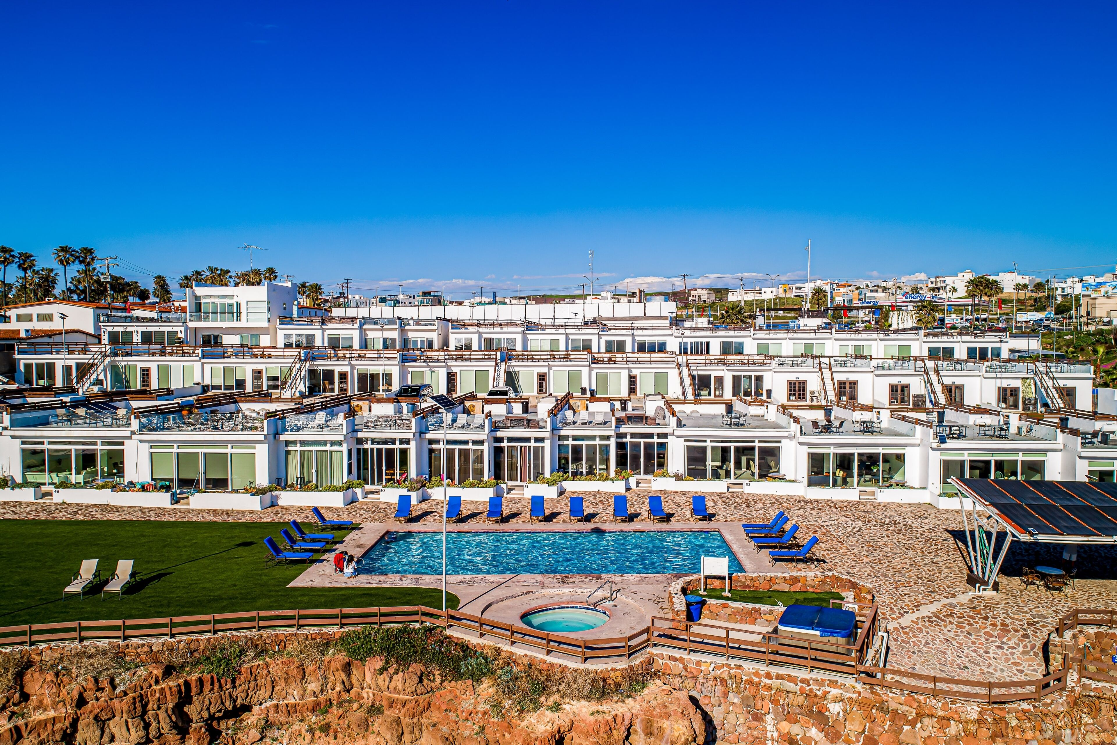 Un grand complexe hôtelier doté de plusieurs piscines, de chaises longues et offrant une vue sur l’océan.