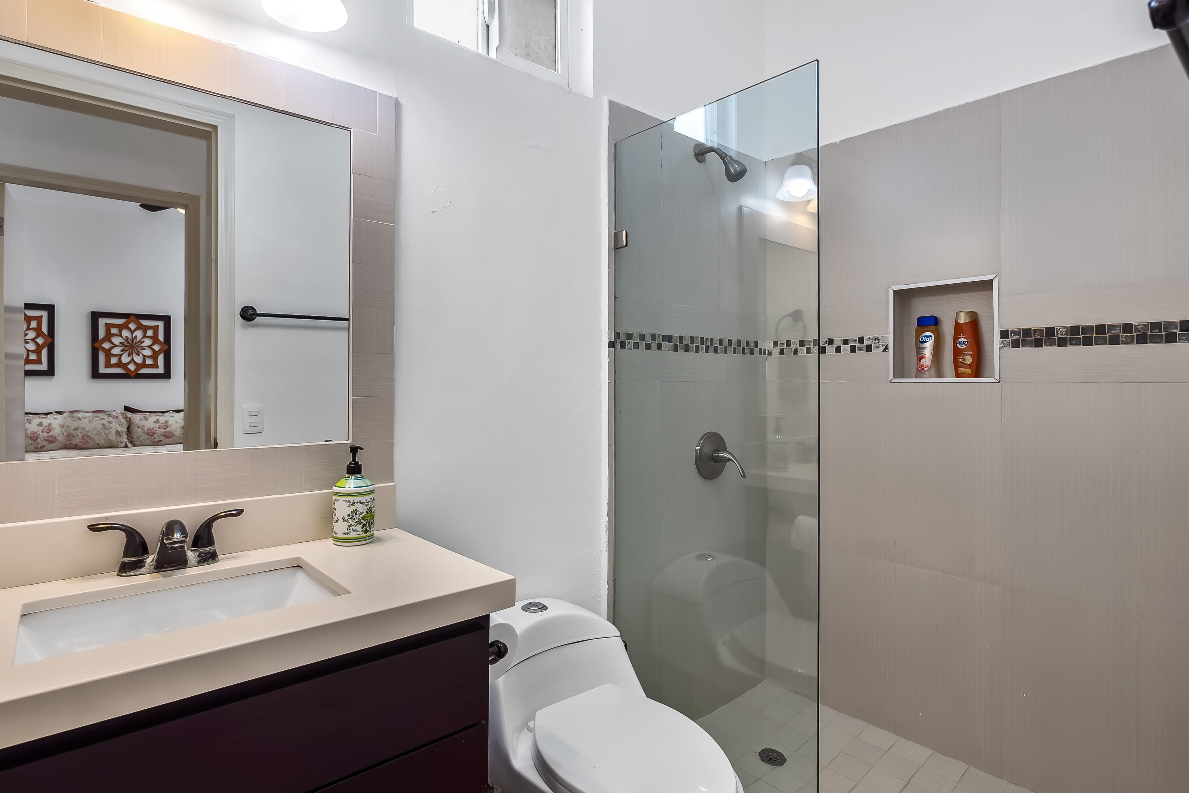 A bathroom with a glass-enclosed shower, a white sink, and a toilet.