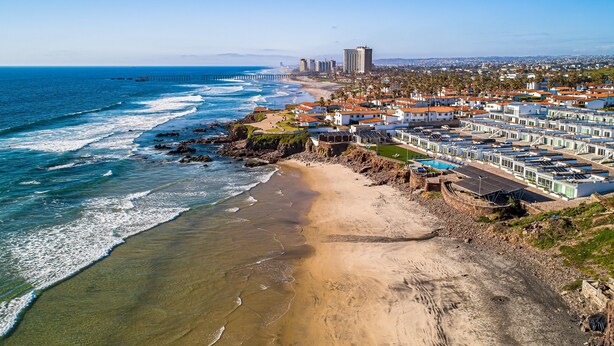 A coastal area with a beach, ocean, and a row of white buildings with red roofs. - Dog-friendly Home With Heated Outdoor Pool, Hot Tub, Balcony, Rooftop Terrace (Playas de Rosarito)