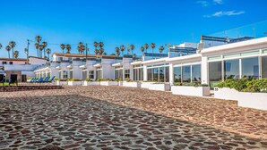 A paved outdoor area with a modern building featuring large windows and a flat roof. - Dog-friendly Home With Heated Outdoor Pool, Hot Tub, Balcony, Rooftop Terrace (Playas de Rosarito)
