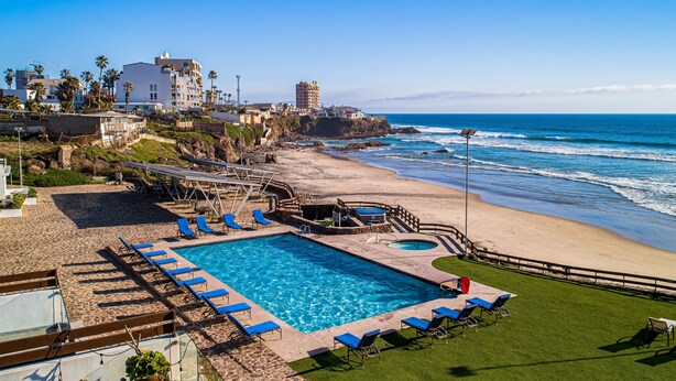 A pool area with blue chairs and a small pool, surrounded by a sandy beach and ocean view. - Dog-friendly Home With Heated Outdoor Pool, Hot Tub, Balcony, Rooftop Terrace (Playas de Rosarito)