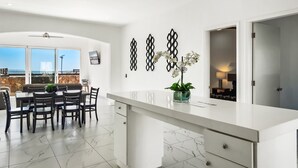 A modern kitchen with a large island, dining area with a table and chairs, decorative wall art, and a view through the windows. - Dog-friendly Home With Heated Outdoor Pool, Hot Tub, Balcony, Rooftop Terrace (Playas de Rosarito)