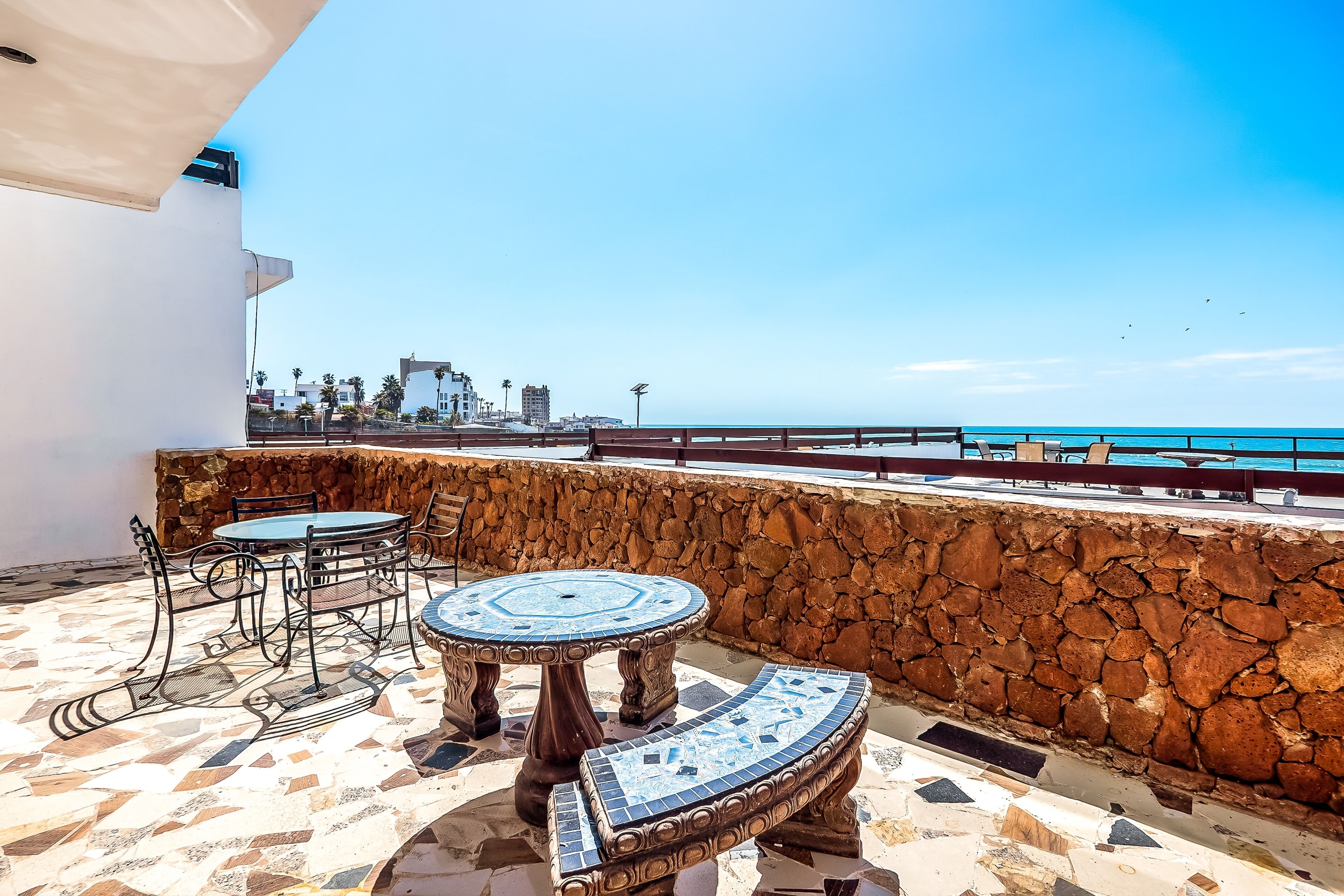 A terrace with a stone wall, a round table, and two chairs.
