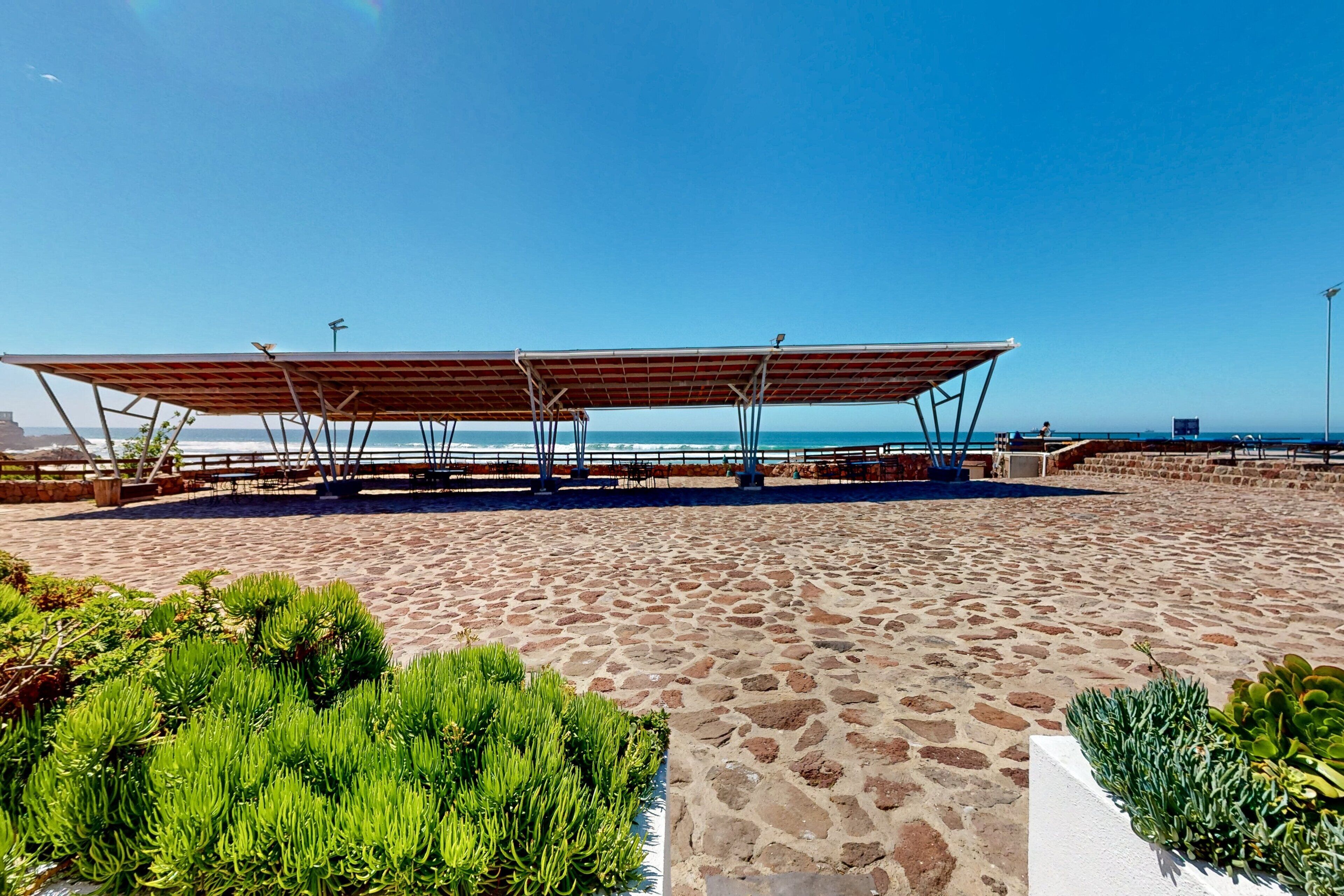 Une plage dotée d’un espace de repos abrité, d’un sentier en pierre et de plantes vertes.