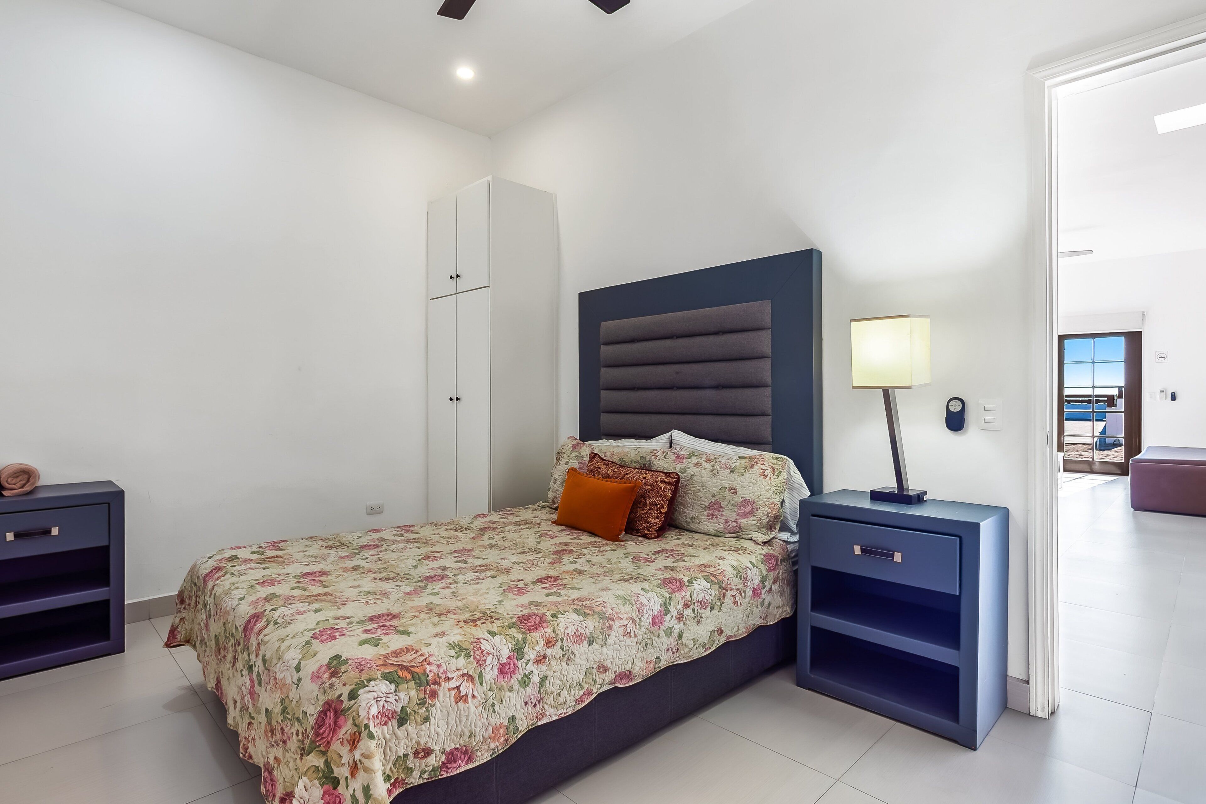 Un dormitorio con cama, mesitas de noche, un armario y una lámpara.