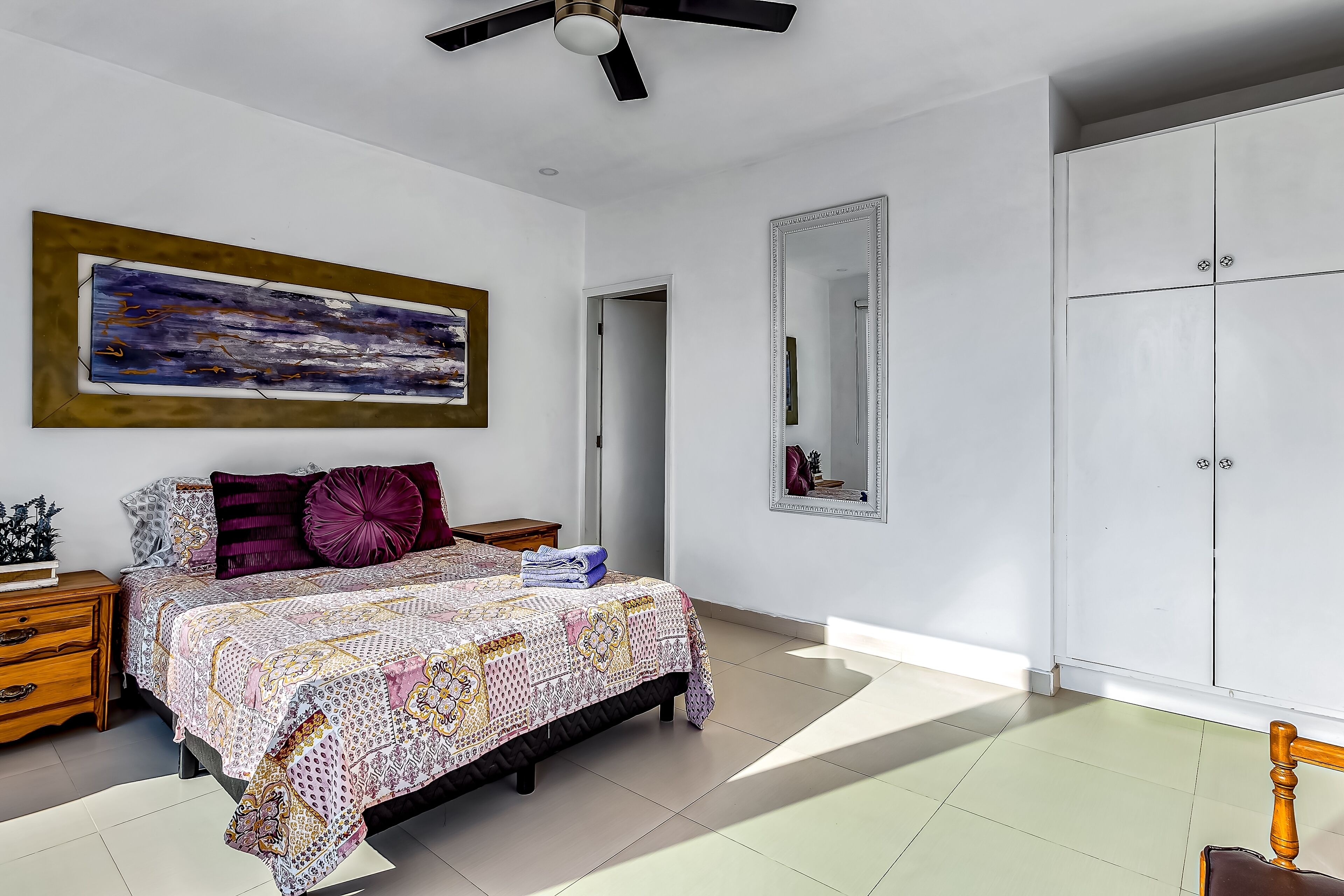 Une chambre à coucher comprenant un lit, une table de chevet, une commode, un miroir et une armoire.
