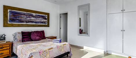 Une chambre à coucher comprenant un lit, une table de chevet, une commode, un miroir et une armoire.