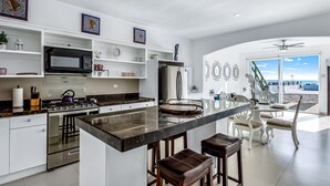 Una cocina moderna con una isla central, taburetes de bar y vistas al exterior.