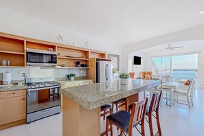 A modern kitchen with granite countertops, stainless steel appliances, and a large island with bar stools. - Dog-friendly Villa With Heated Outdoor Pool, Hot Tub, Streaming, Balcony, Grill (Playas de Rosarito)