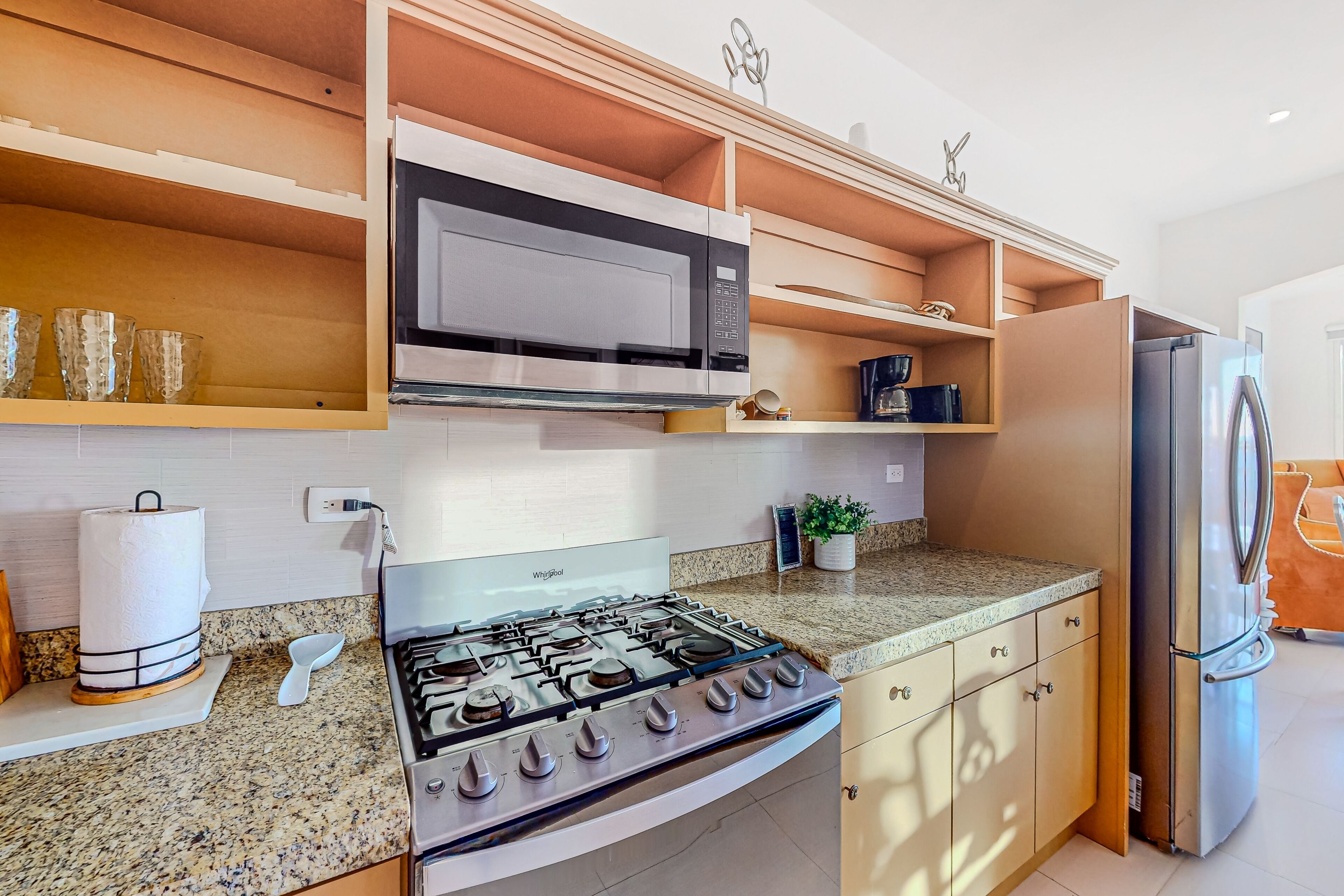 A modern kitchen with a gas stove, microwave, and stainless steel refrigerator.