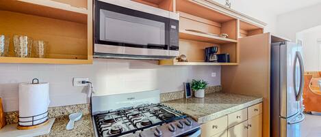 A modern kitchen with a gas stove, microwave, and stainless steel refrigerator.