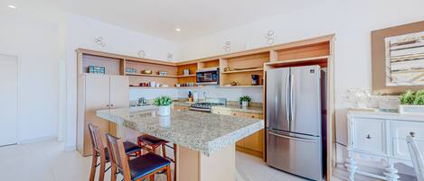 Een moderne keuken met een centraal eiland, roestvrijstalen apparatuur en houten kastjes.