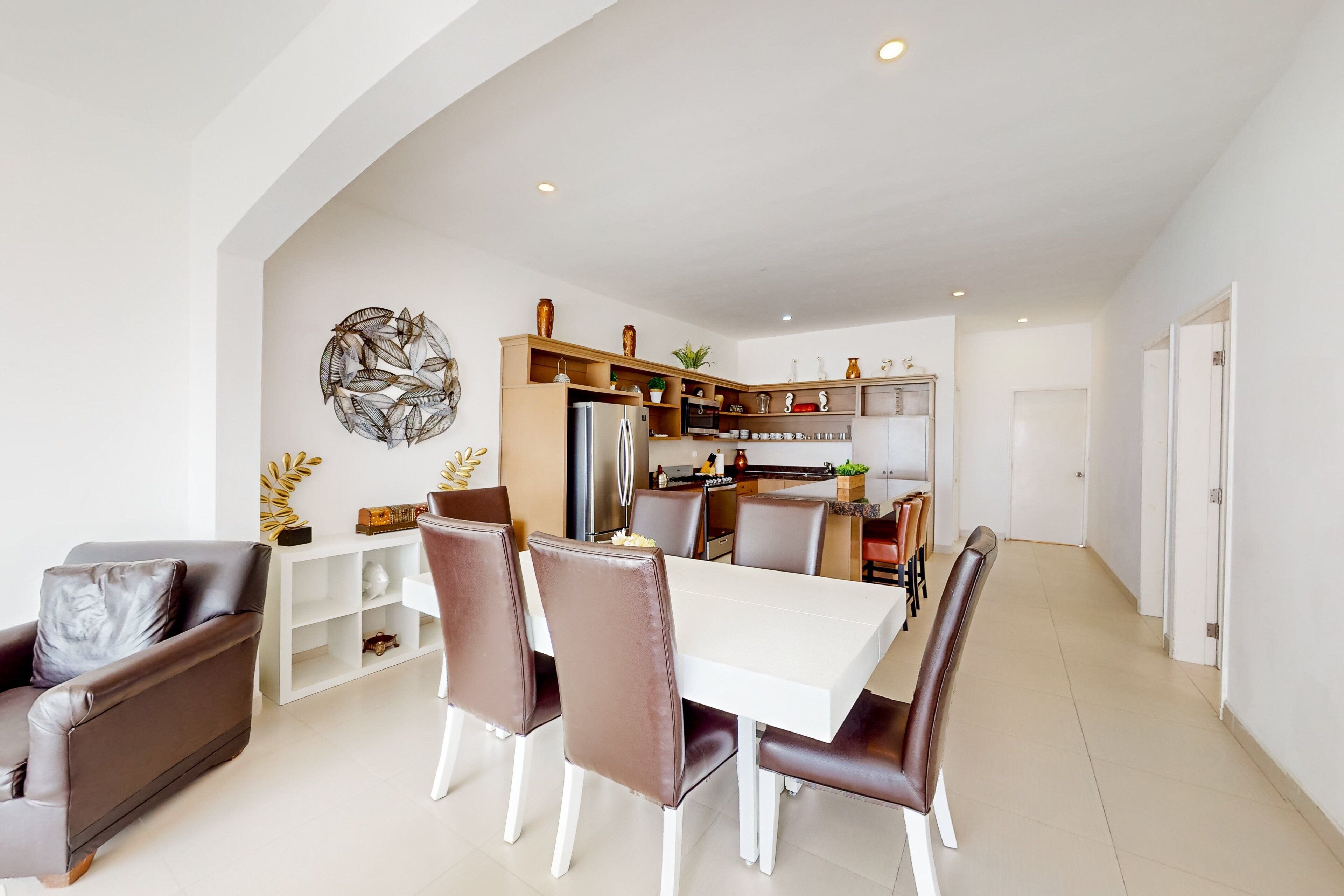 A modern kitchen with a dining area, white walls, and a white ceiling.