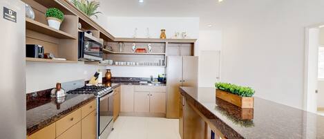 A modern kitchen with granite countertops, stainless steel appliances, and wooden cabinets.