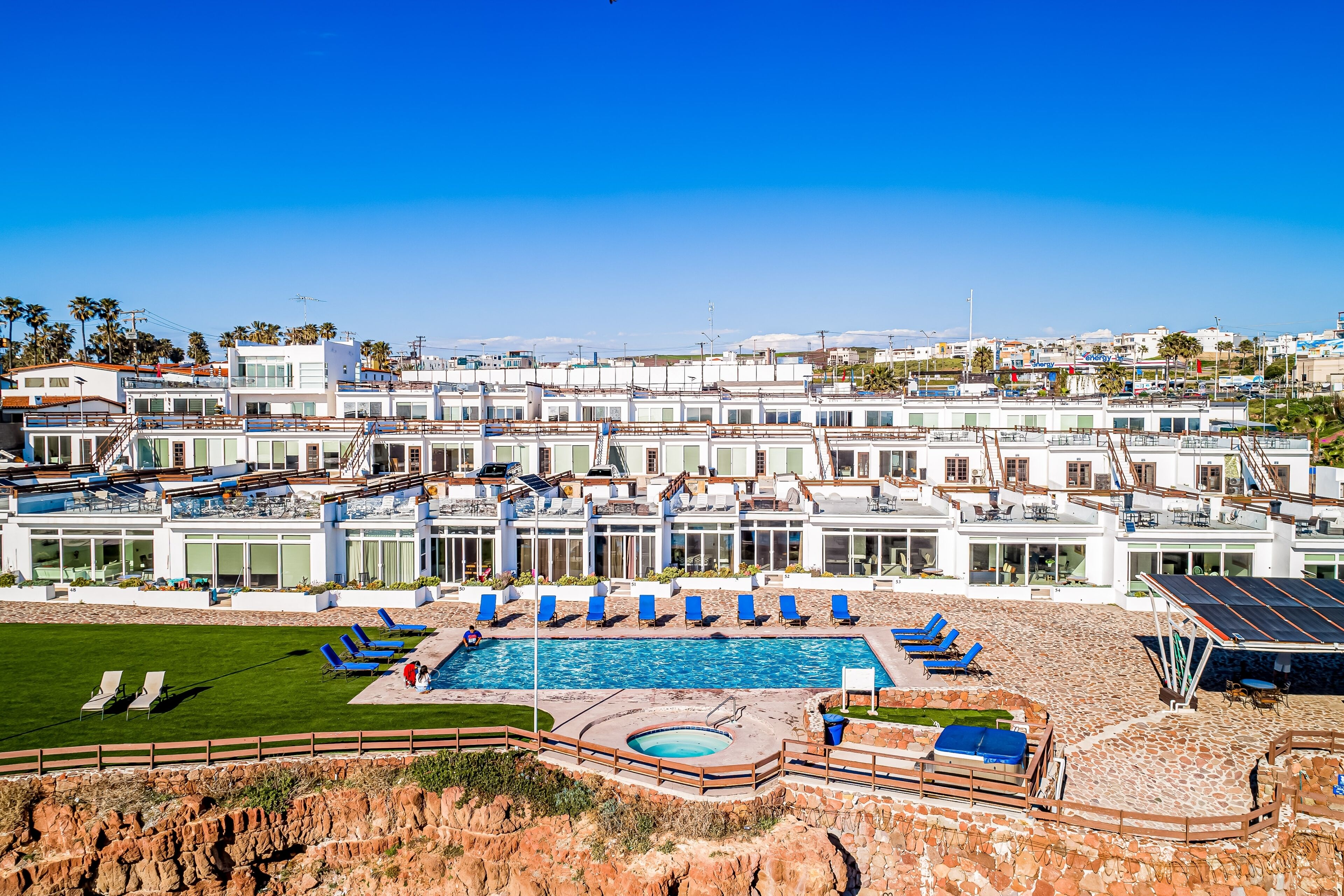 Ett semesterhotell med en swimmingpool, solstolar och utsikt över havet.