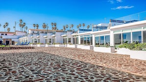 Un hotel con patio empedrado, palmeras y arquitectura moderna.