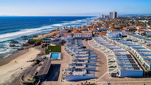Un hotel frente al mar con varias construcciones, una playa y un muelle.
