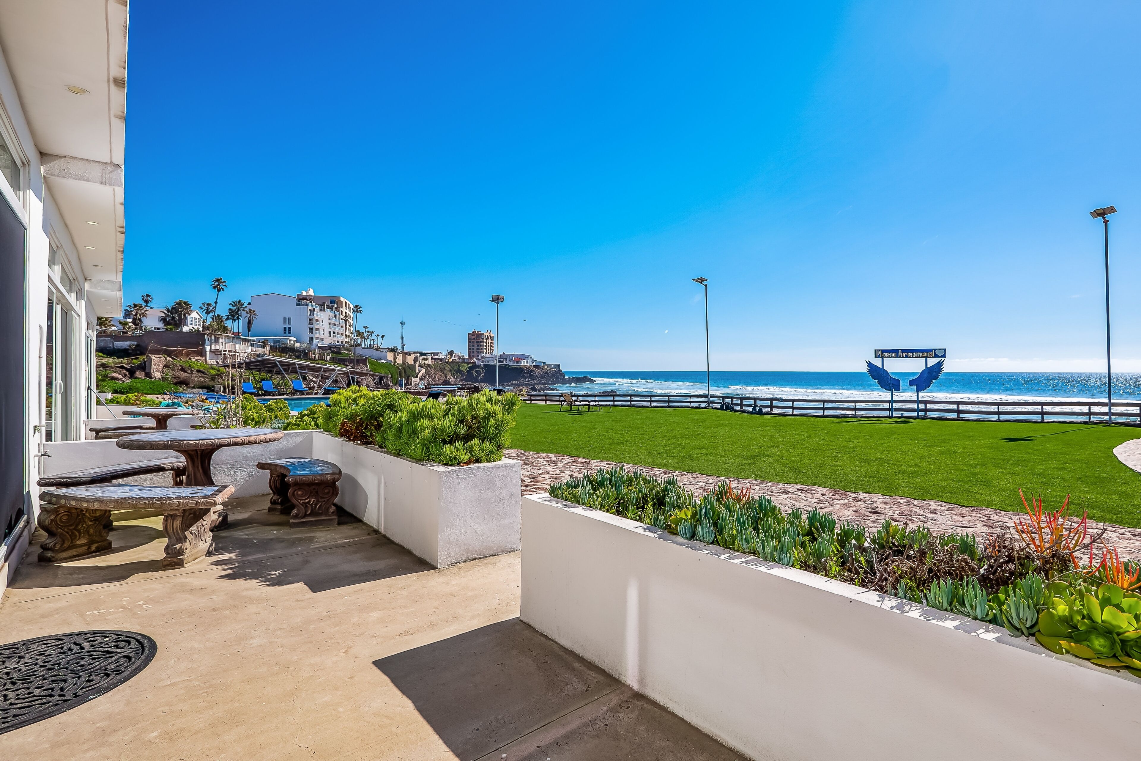 A balcony with outdoor seating, a view of the beach, and a sign reading "Casa Arconada."