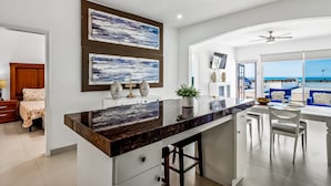 A modern kitchen with a central island, a dining area with a view, and a living room with a large window. - Dog-friendly Villa With Heated Outdoor Pool, Hot Tub, Streaming, Private Patio (Playas de Rosarito)
