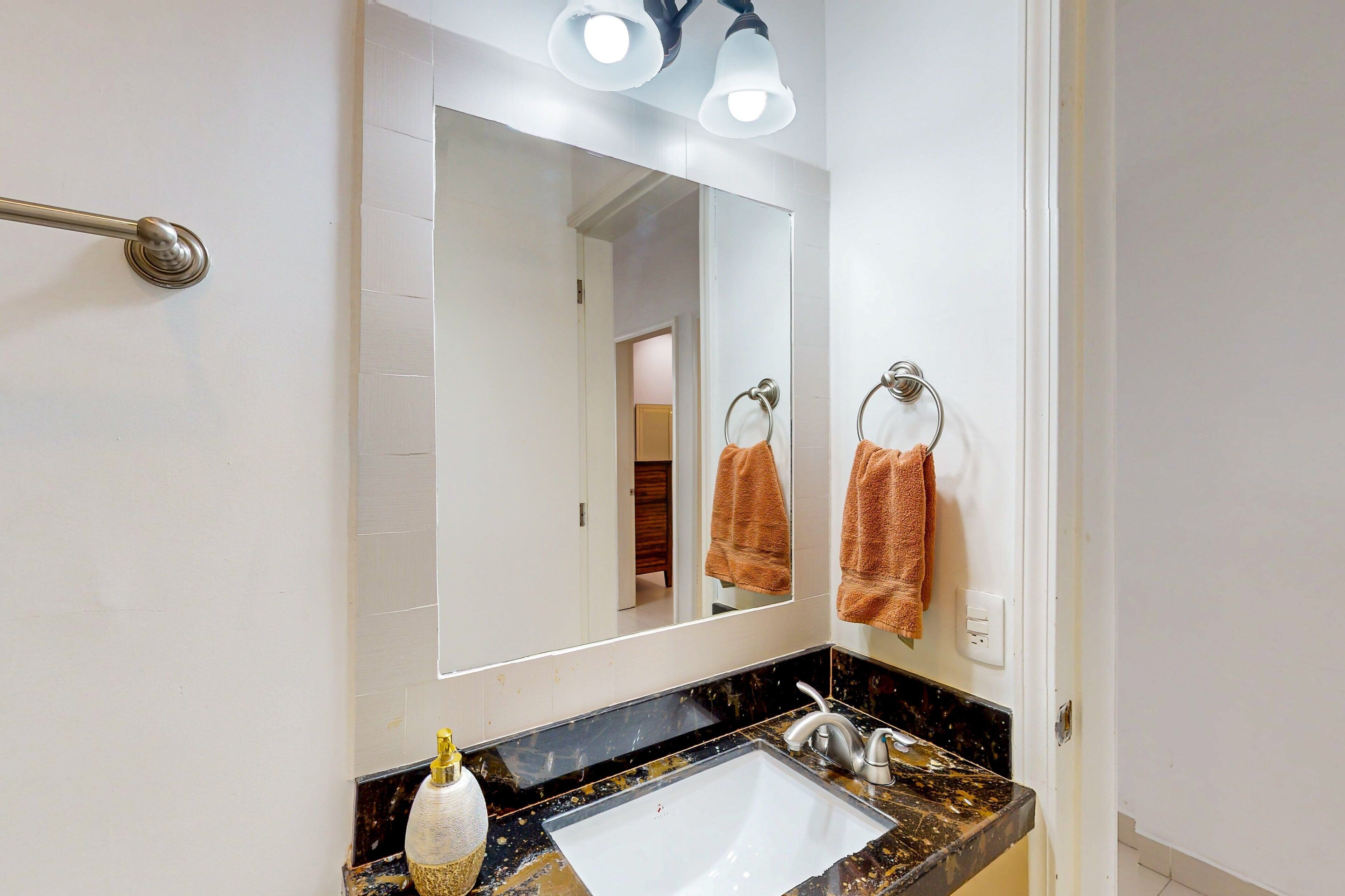 Une salle de bain avec un lavabo blanc, un miroir et deux porte-serviettes.