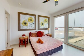 A bedroom with a bed, a small table, a chair, a nightstand, and a window with a view. - Dog-friendly Villa With Heated Outdoor Pool, Hot Tub, Streaming, Partial Views (Playas de Rosarito)