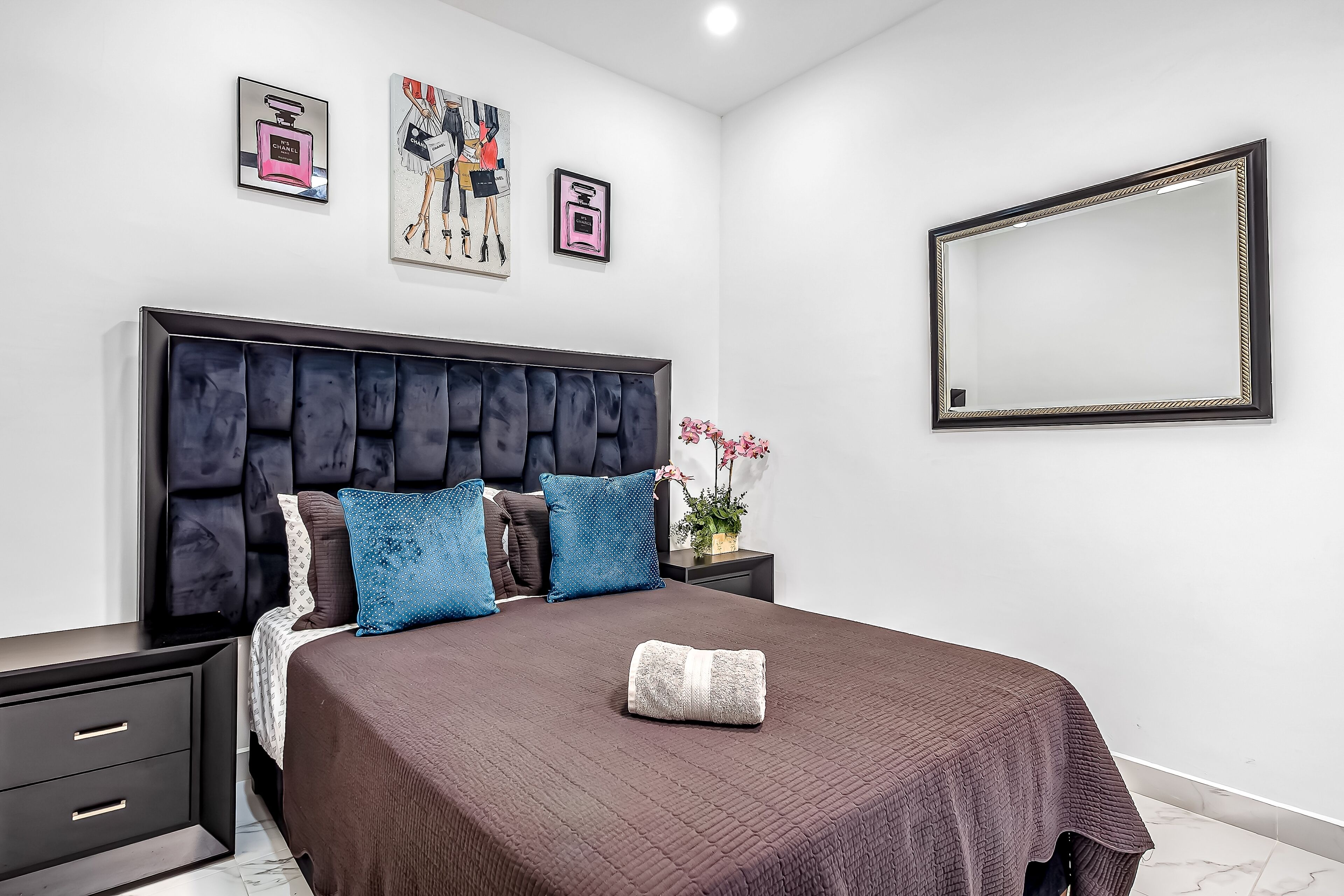 Ein modernes Schlafzimmer mit einem großen Bett, einem dunklen Kopfteil und dekorativen Kissen.