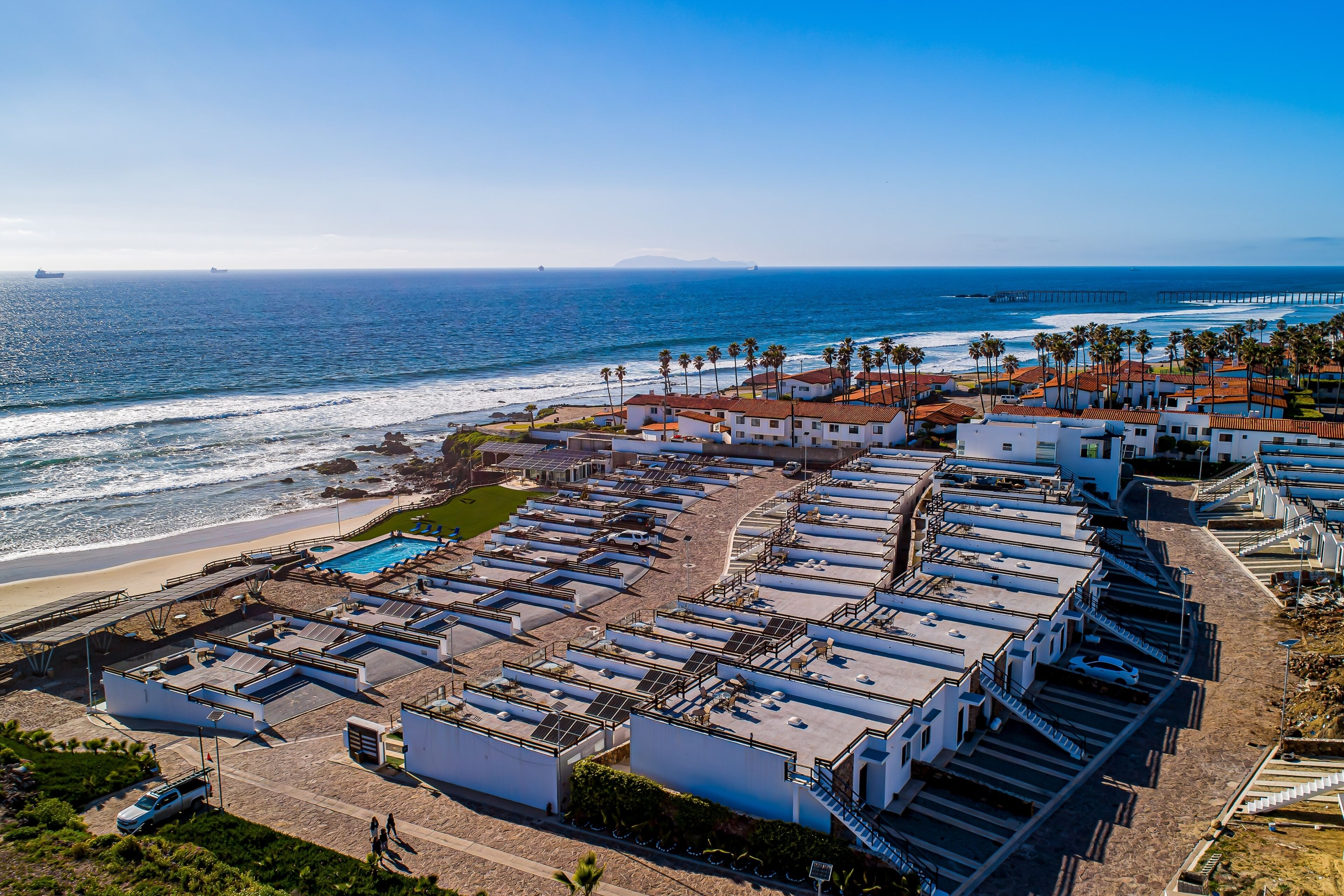 Un hôtel situé sur la côte, composé de plusieurs bâtiments, doté d’une piscine et offrant une vue sur la plage.